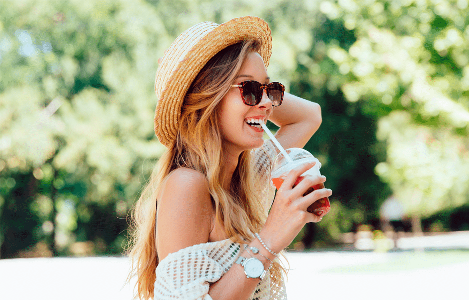 Une jeune fille boit un verre à la paille dans un parc au soleil et se fait prendre en photo par un photographe Lifestyle en Nouvelle Aquitaine 