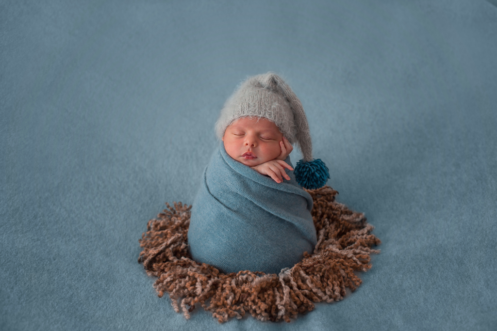 nouveau-né se fait prendre en photo dans un studio photo en Occitanie est enroulé dans une couverture 